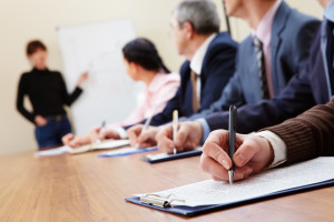 Row of business people making notes during presentation